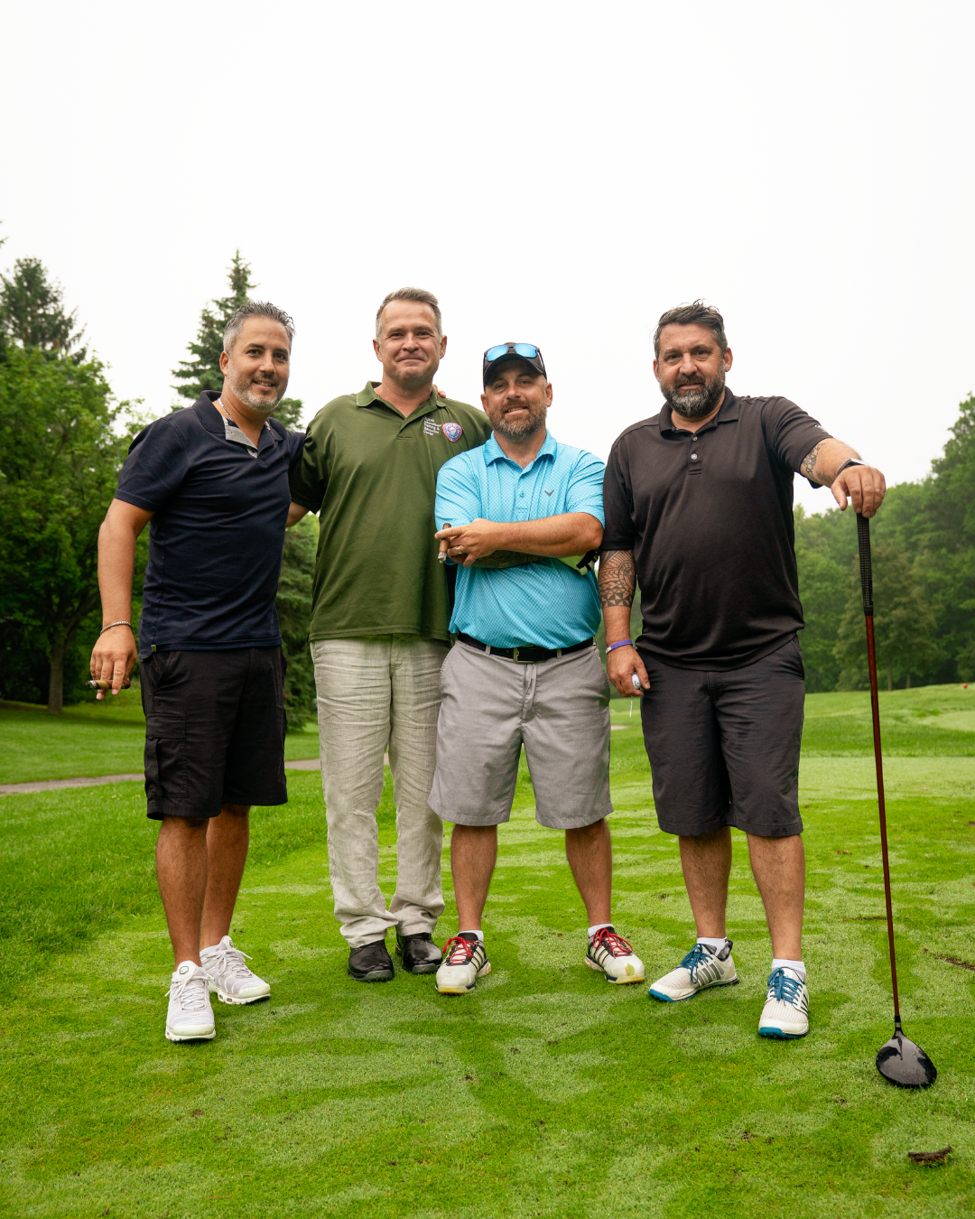 4 OETIO Staff members stand side by side on a golf course.
