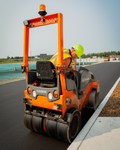 A man on an orange machine paving a road