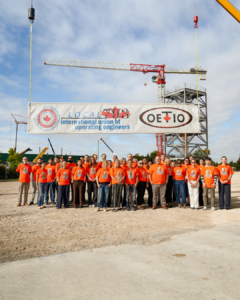 793 staff wearing orange shirts standing in front of a hanging banner reading