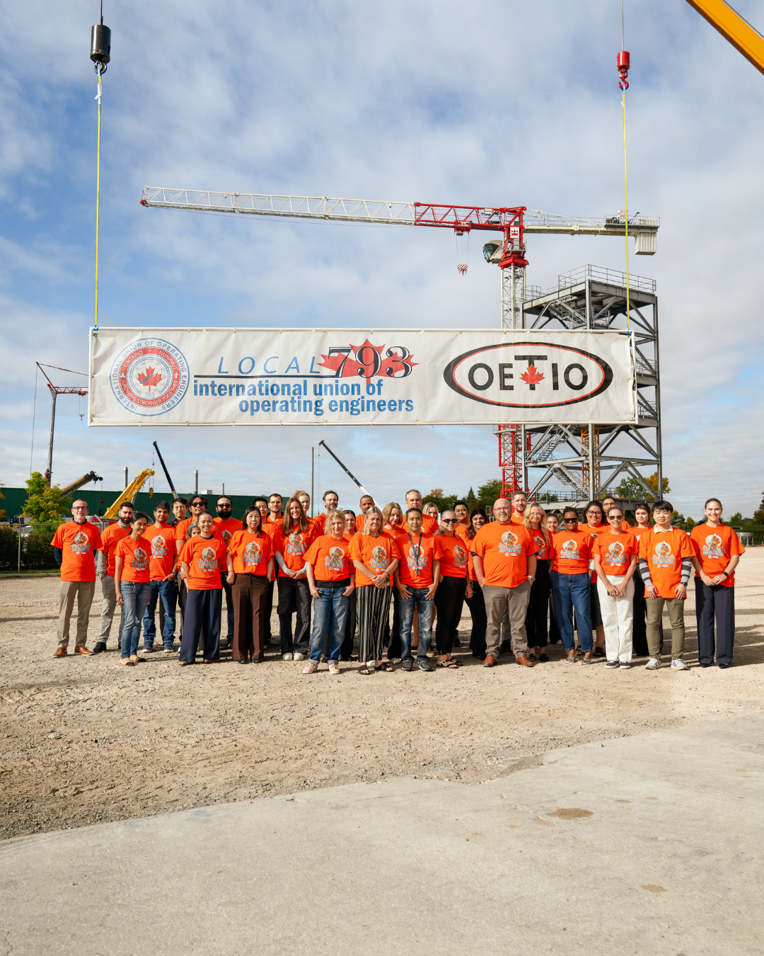 793 staff wearing orange shirts standing in front of a hanging banner reading