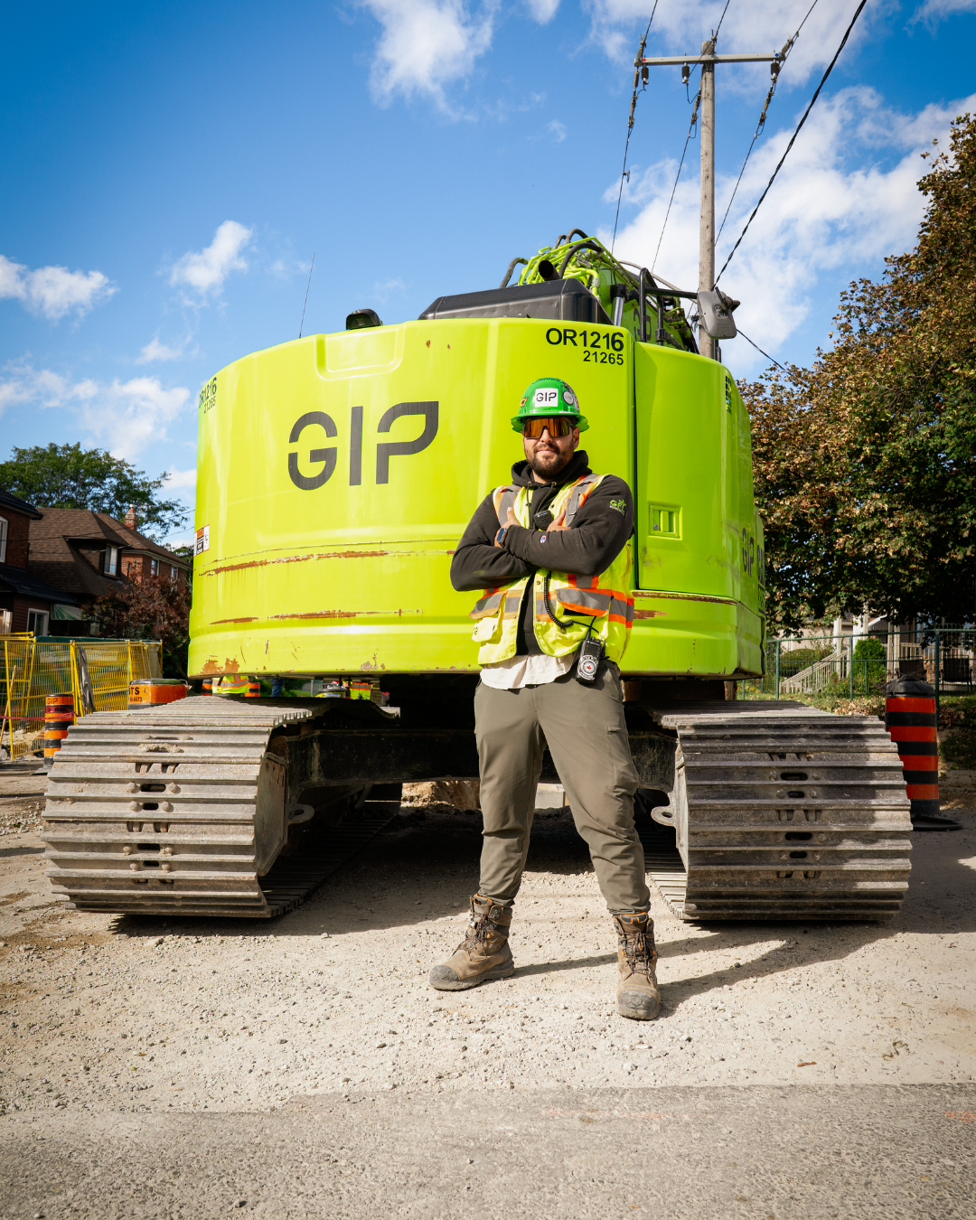 793 Member Eduardo Pinheiro wearing a green hard had and proper P.P.E stands in front of a green excavator