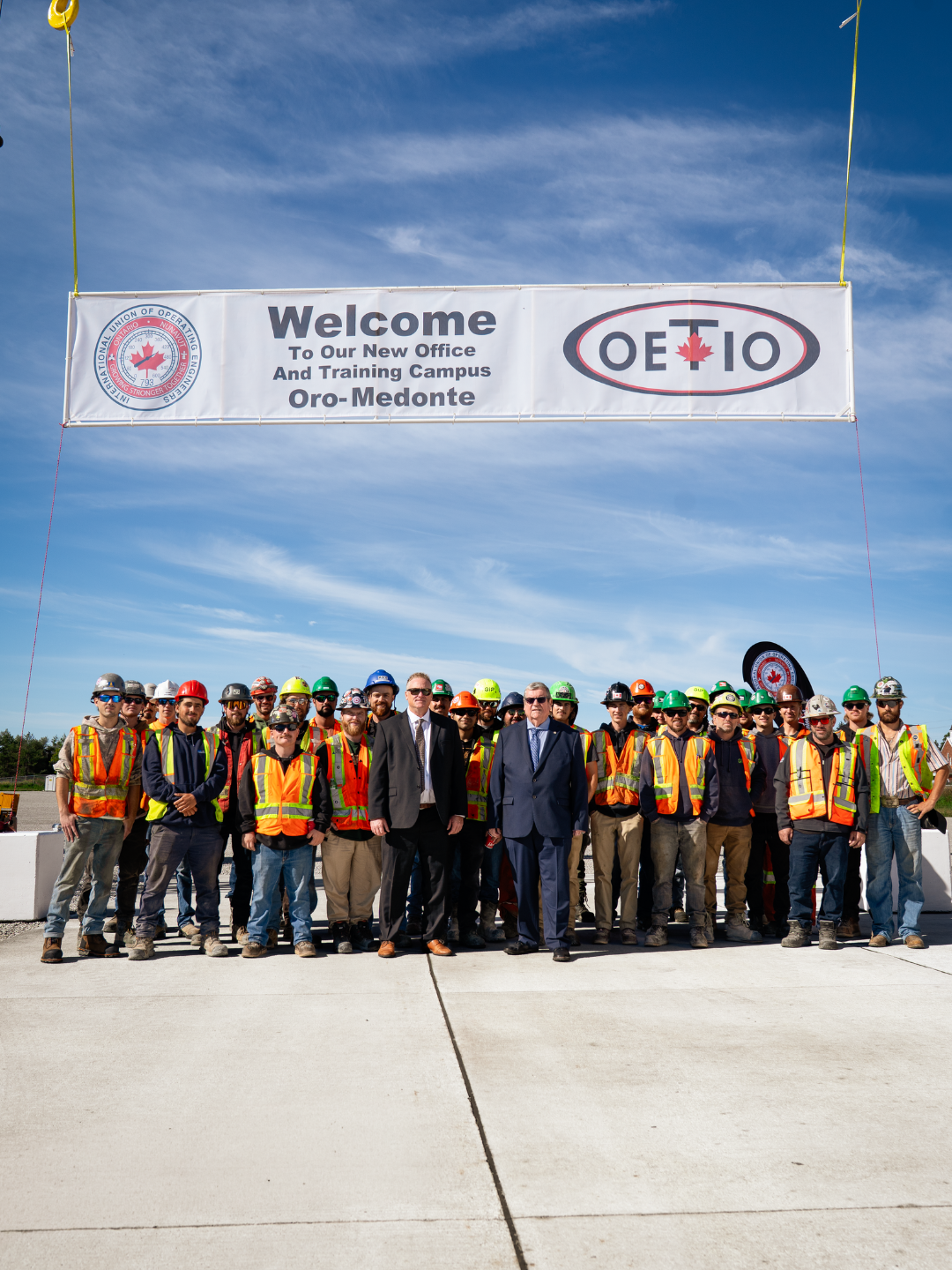 Dave Turple and Mike Gallagher stand with apprentices in front of a banner which reads:
