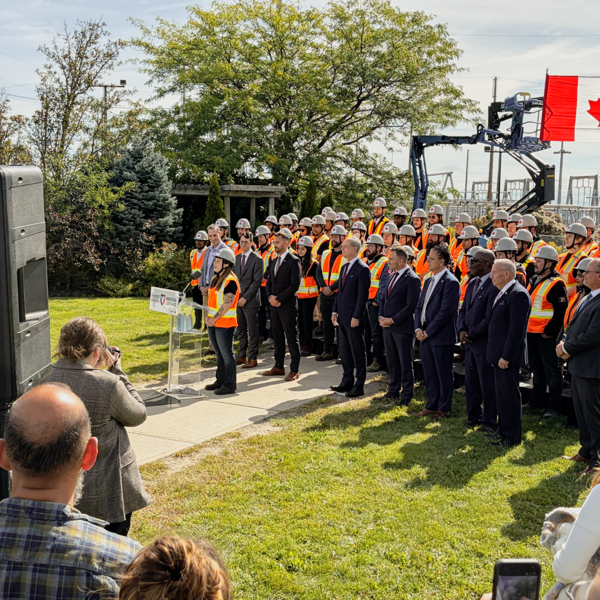 A group of construction workers standing with one of them giving a speech to others