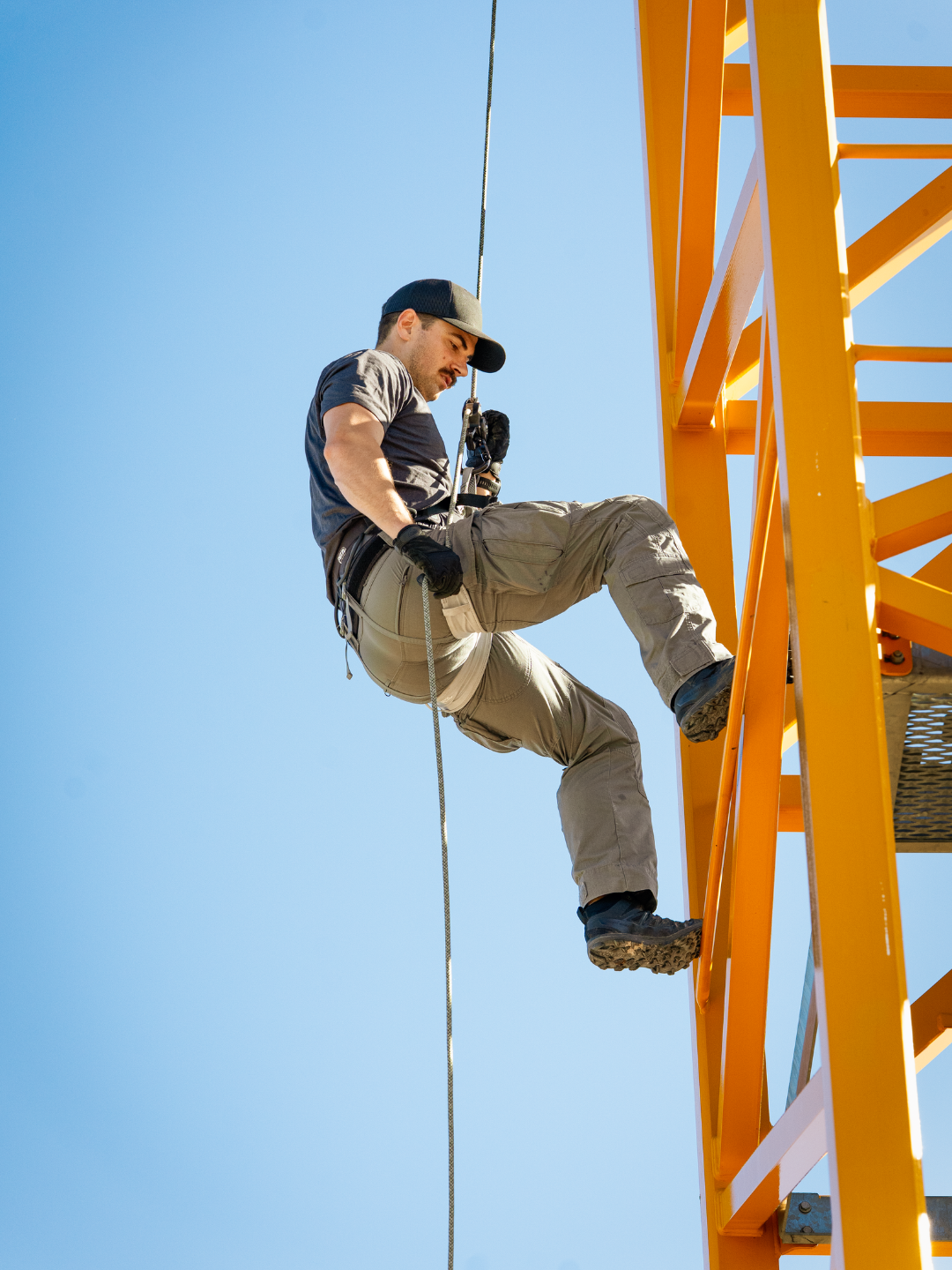 A man rappelling down the side of a crane