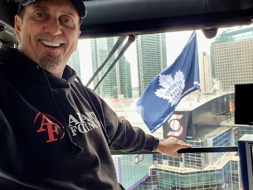 Member inside crane posing in front of the Toronto Maple Leafs glad and the Scotiabank Arena