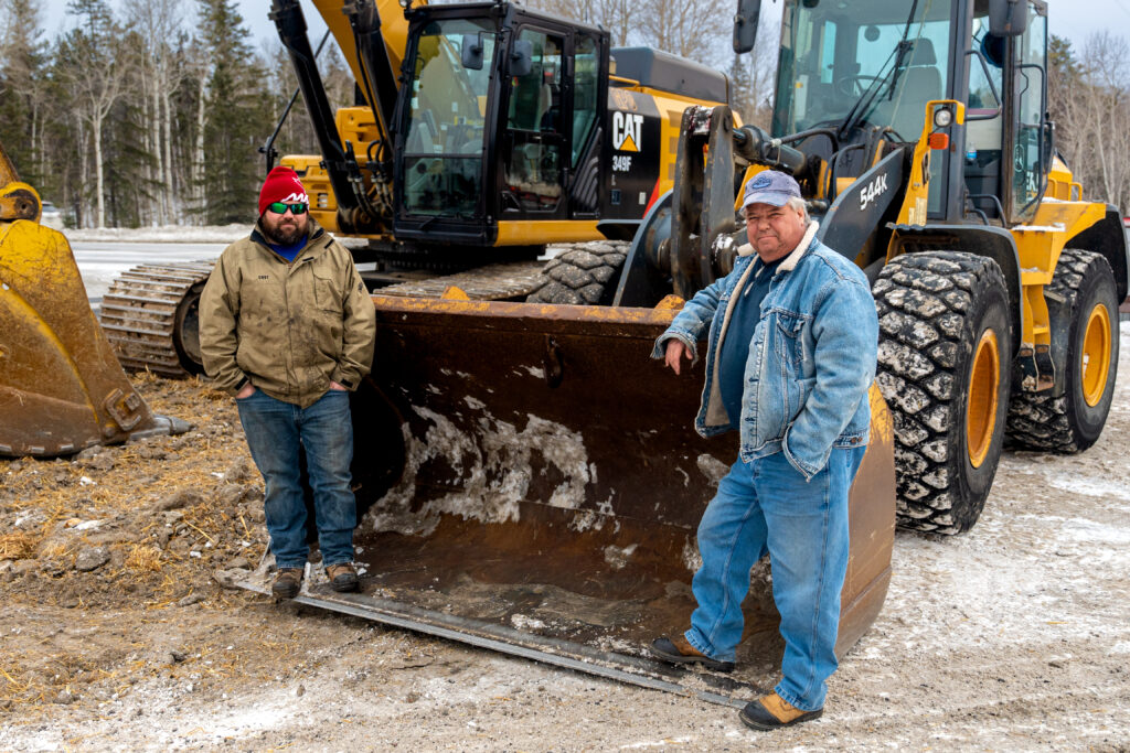 Two members standing and leaning on a dozer on site