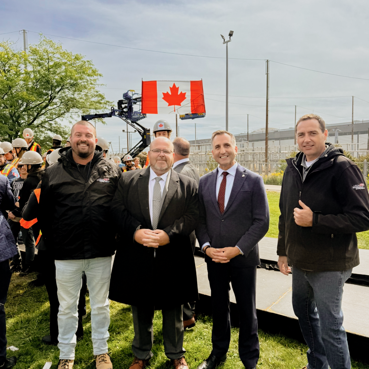 4 men stand side by side with the Canadian Flag behind them
