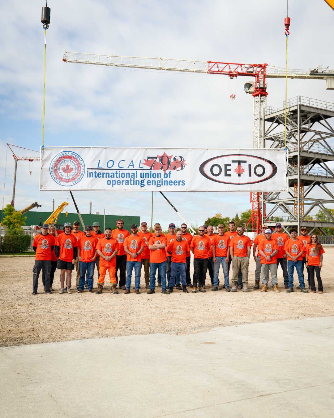 OETIO apprentices and staff wearing orange shirts standing in front of a hanging banner reading