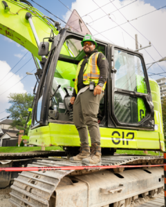 793 member Eduardo Pinheiro is wearing a green hard hat and proper P.P.E and stands on an excavator track