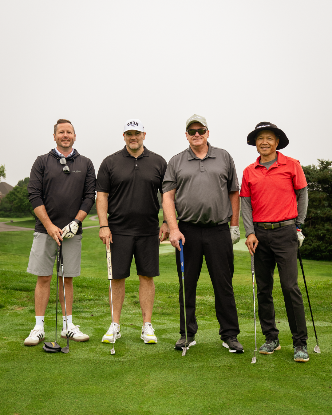 Justin O'Neill (left), Bob Brooks, (middle left), Dave Turple (middle right) and Ken Lew (right) stand side by side smiling on a golf course.