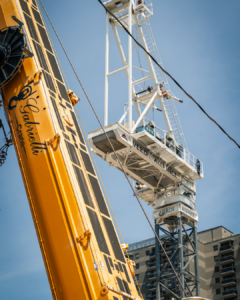 A white and blue crane with the mast of a yellow crane in the foreground