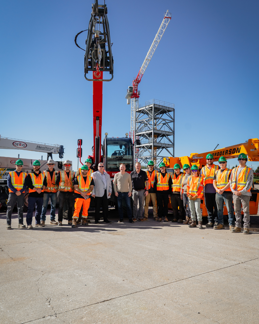 Numerous OETIO apprentices stand with Mike Gallagher (centre left), Dave Turple (centre right) and Sean O"Meara (centre middle) in front of a crane