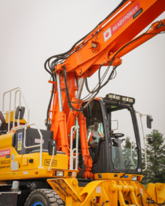 a close up shot of an operating engineer sitting inside an orange and yellow High Rail Excavator