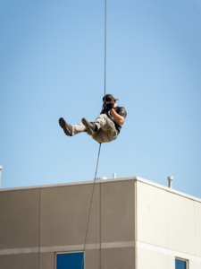 A man stapped in with proper safety equipment mid air as he rappels down a crane.