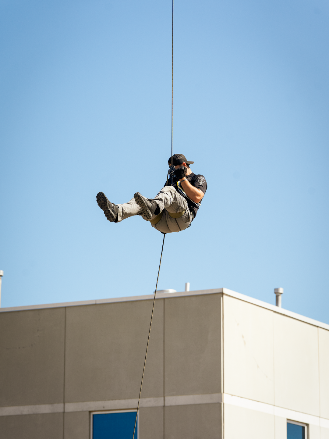 A man stapped in with proper safety equipment mid air as he rappels down a crane.