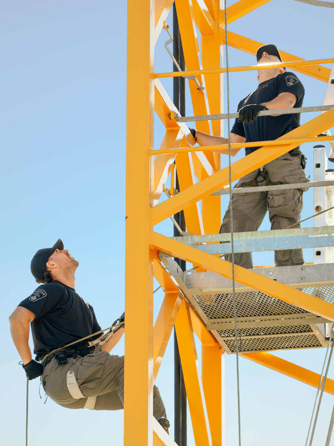 A man rappelling down the side of a crane