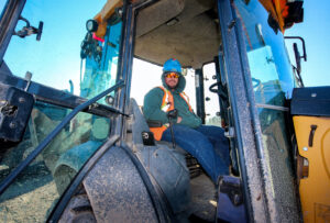 Richard Olinski sits in the cab of his John Deere 310 backhoe.
