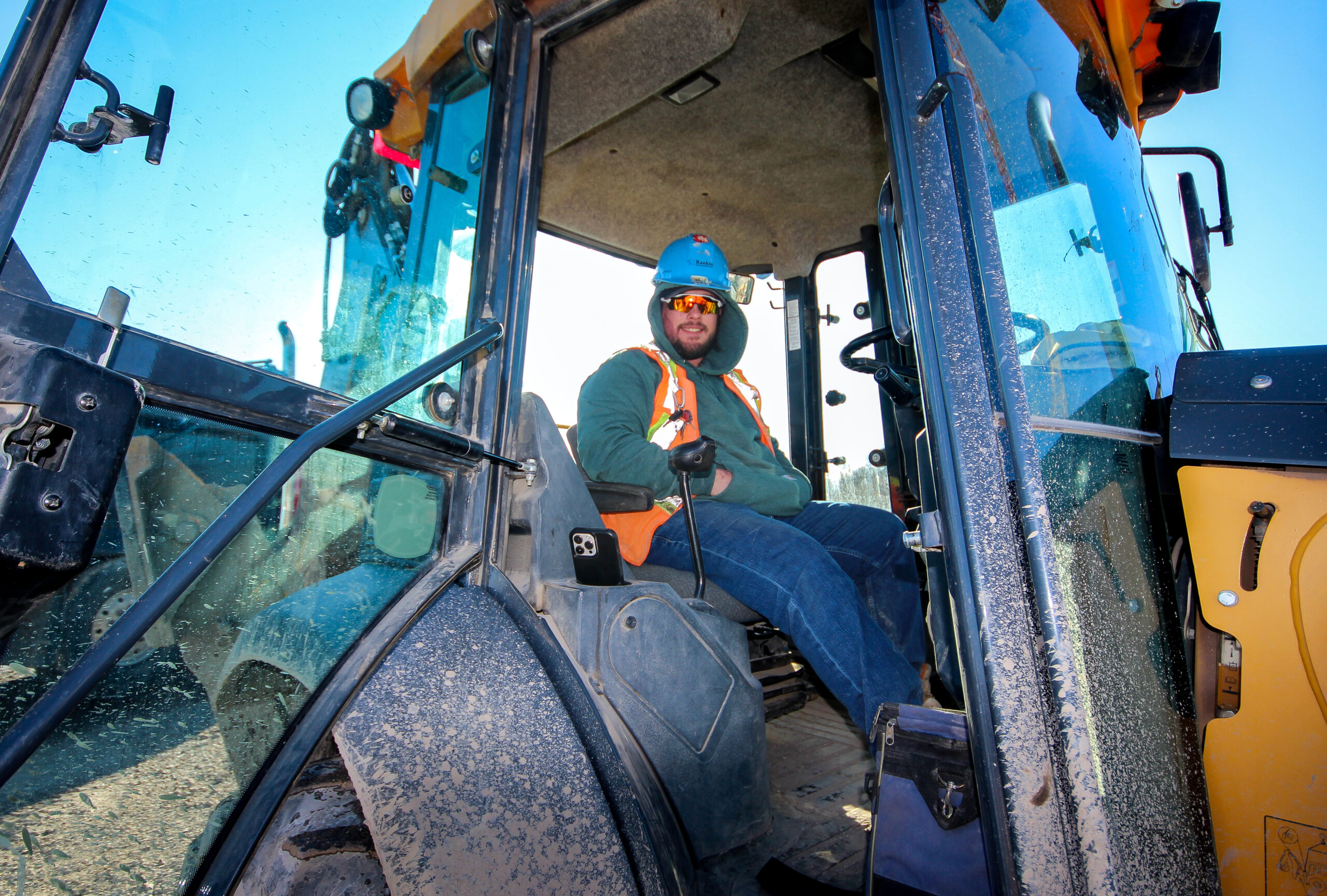 Richard Olinski sits in the cab of his John Deere 310 backhoe.