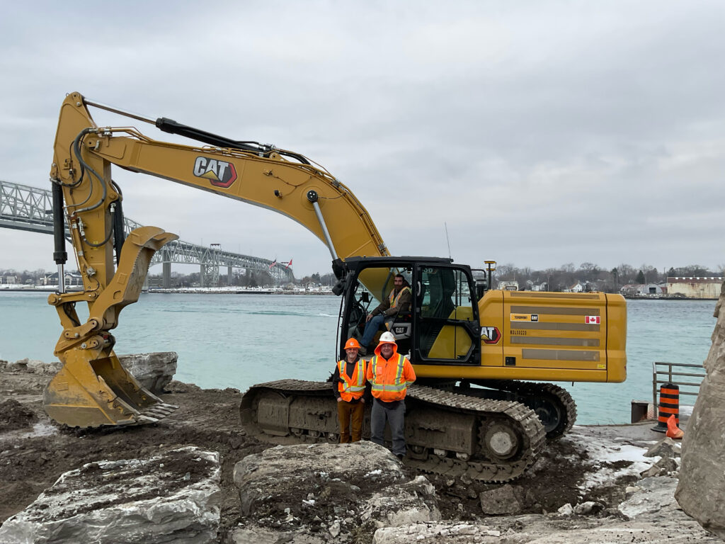 Brothers Joe Cogghe and Brian Ballard standing, and Rob Wellington in CAT excavator on waterfront site