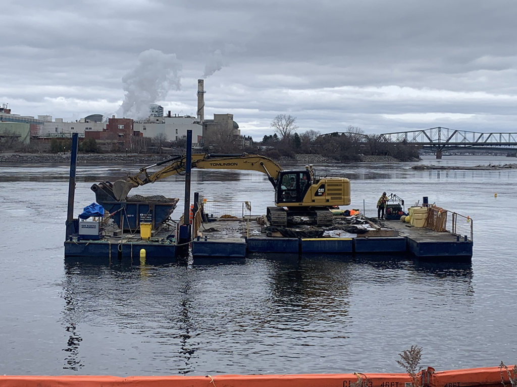 Wide shot of the excavator on a platform in the middle of the water