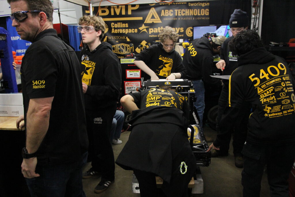 Pit crew works on robot.