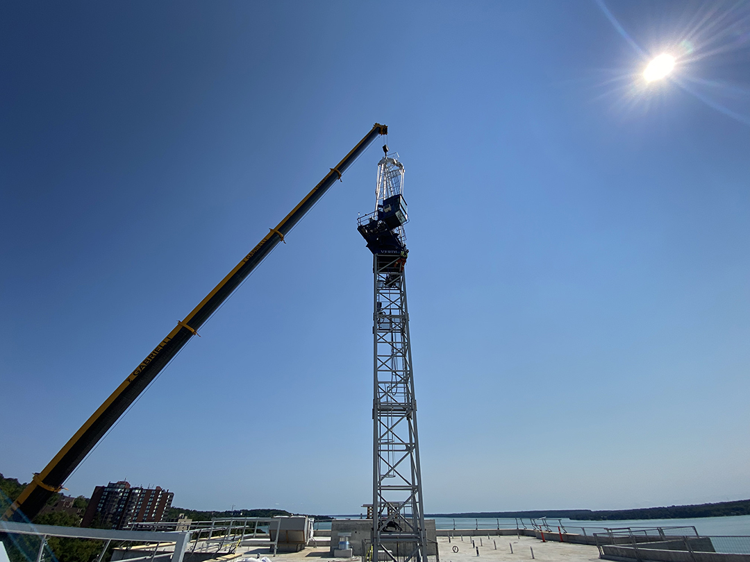 Ground shot of the tower and crane beneath the blue sky and sun