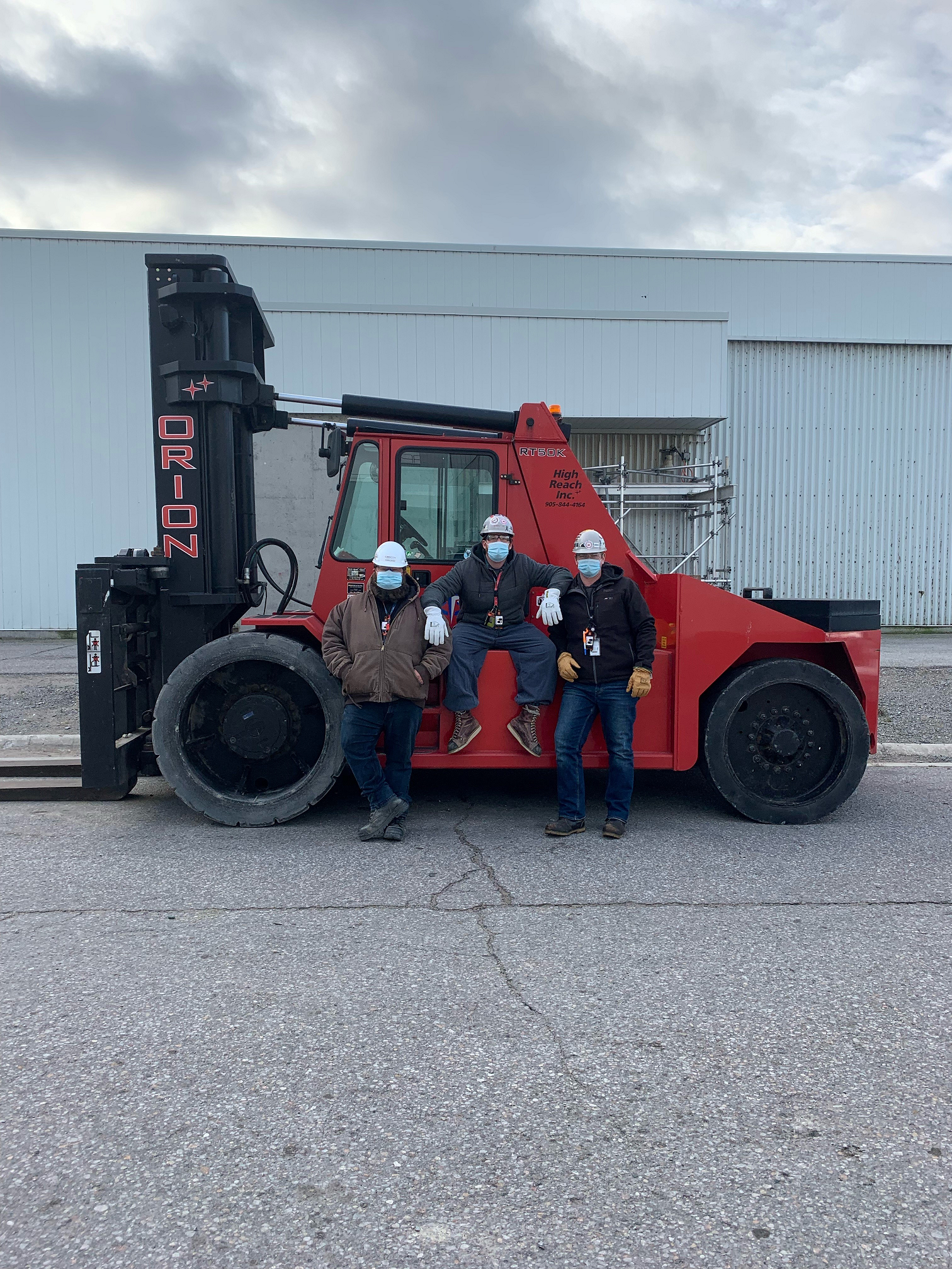 homas Lintner, Christopher Calcafuoco and Brad Martin posing on an Orion RT50K forklift.