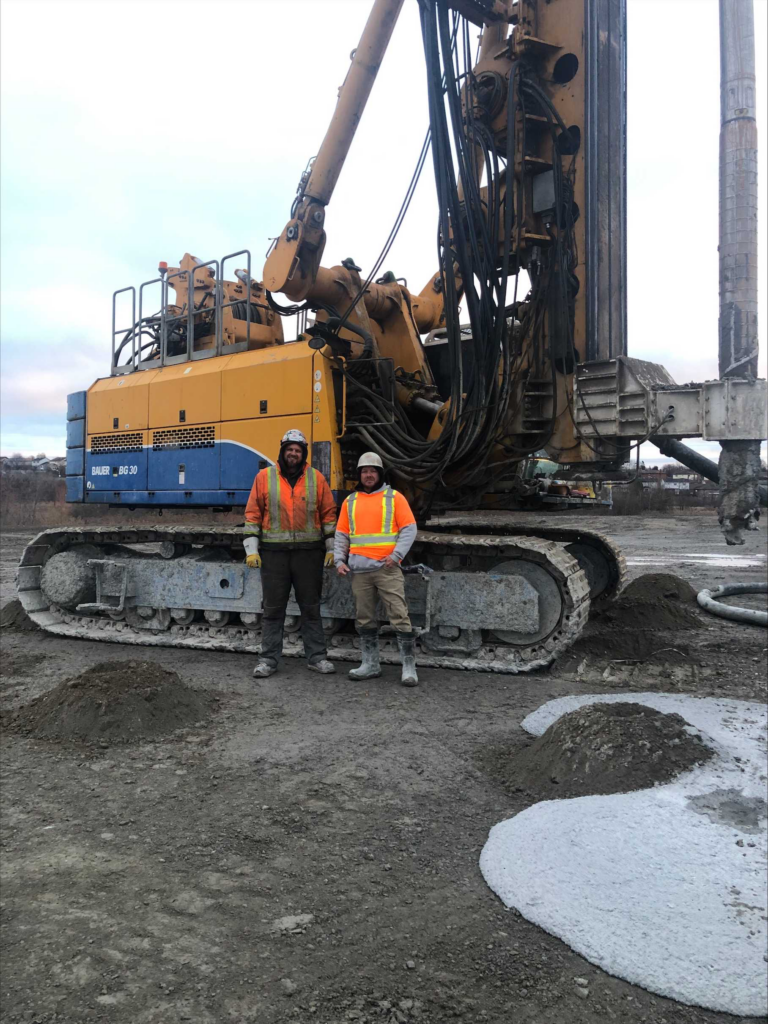 Members standing in front of a Bauer BG 30- Rotary Drilling Rig on site 