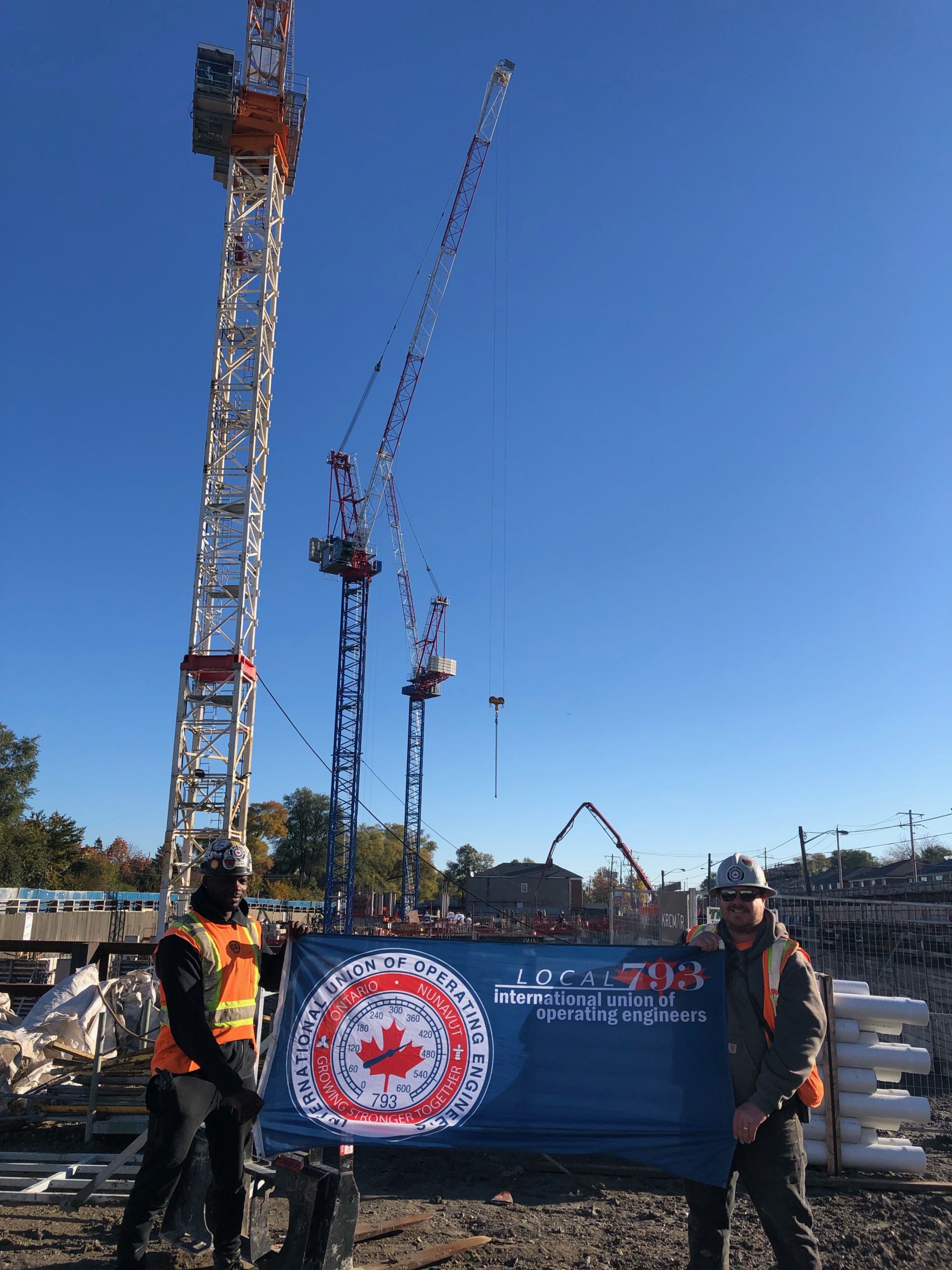 Local 793 apprentice Randy Sarba and Jesse Martin show their Local 793 pride in front of three tower cranes.