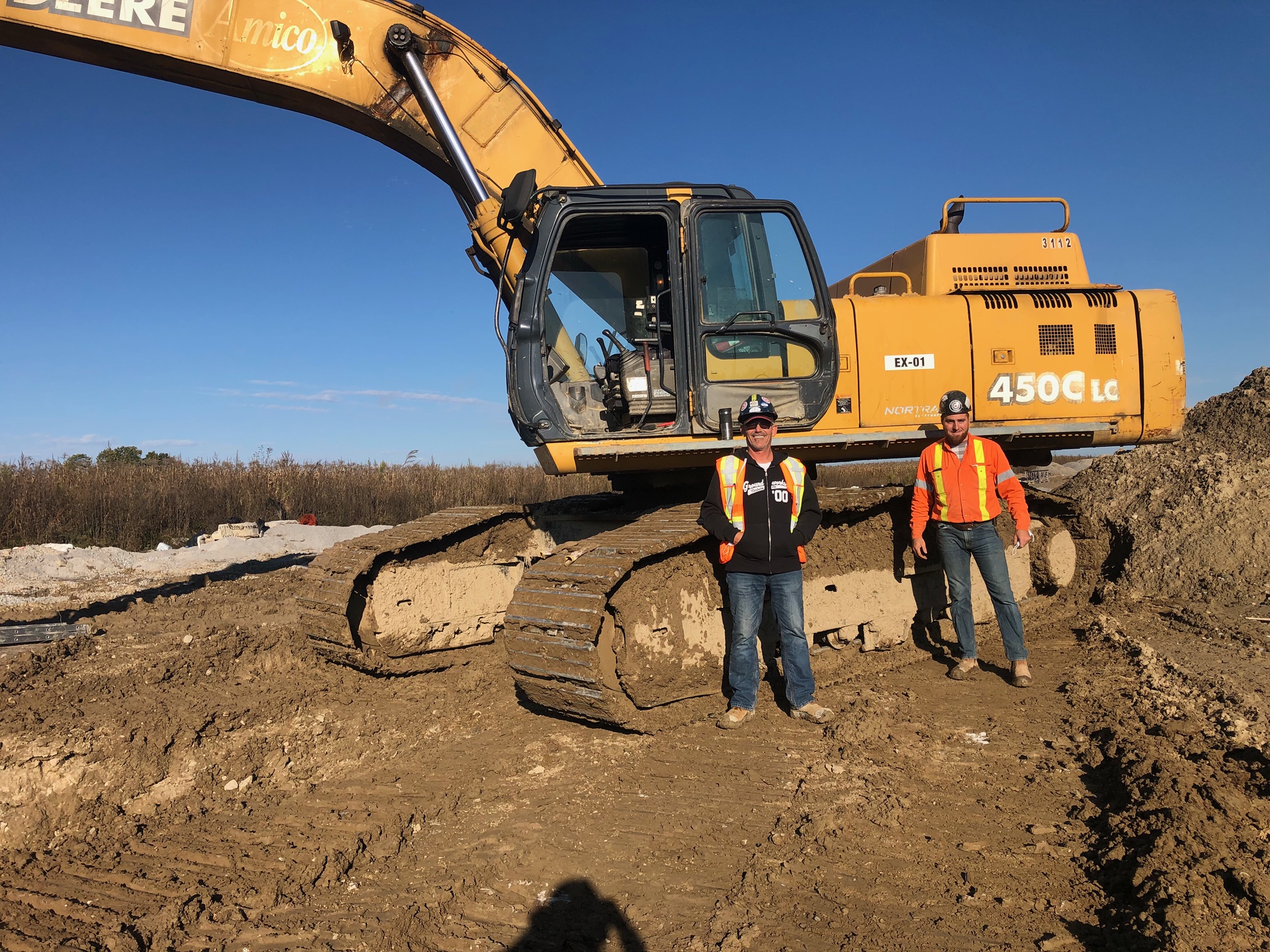 Local 793 members Dave Mizzau and Stephen Carlton standing in front of a John Deere 450C excavator.