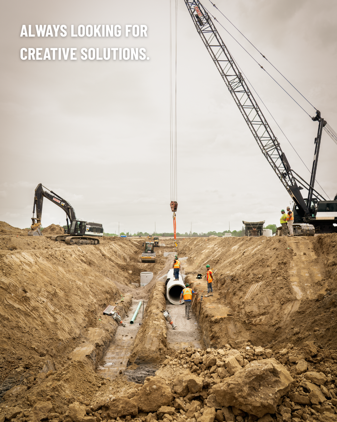 An image of a barren, dirt filled landscape with a excavator and a crane. Text in the top left corner reads: Always looking for creative solutions.