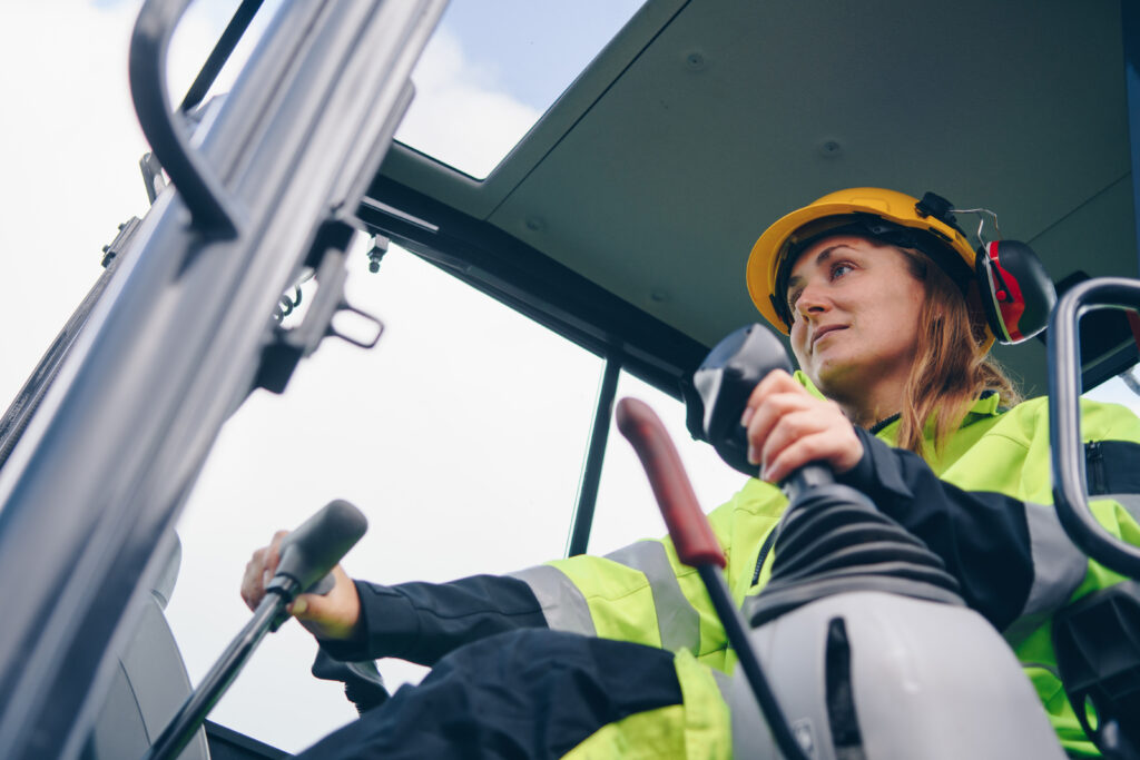 Low perspective shot of a women inside cab of heavy equipment operating